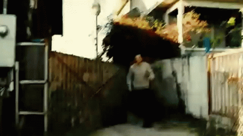 A Man In A Sweater Is Running Down A Sidewalk GIF