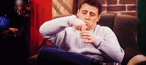 a man in a sweater is sitting in a chair with his legs crossed .