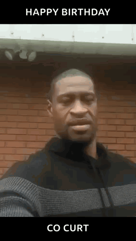 A Man In A Sweater Is Standing In Front Of A Brick Wall And Says Happy Birthday Co Curt . GIF