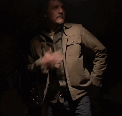 A Man In A Tan Jacket And Cowboy Hat Is Dancing In The Dark GIF