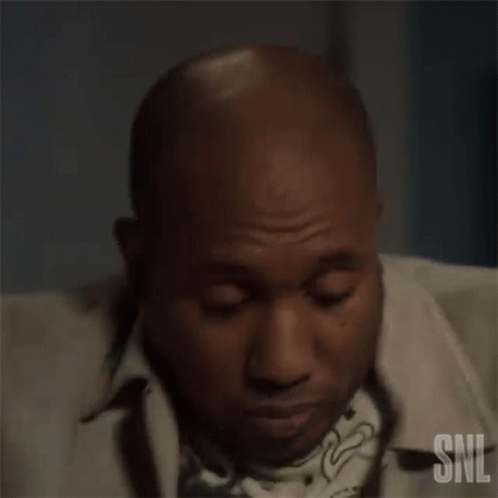 A Man In A Tan Jacket Is Holding His Chest . GIF