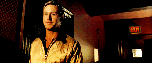 A Man In A Tan Jacket Stands In Front Of An Exit Sign GIF