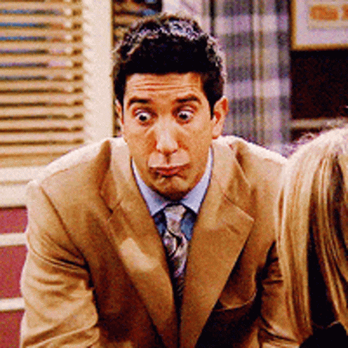 A Man In A Tan Suit And Tie Making A Funny Face GIF