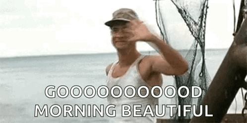 A Man In A Tank Top And Hat Is Waving At The Camera While Standing On A Boat In The Ocean . GIF