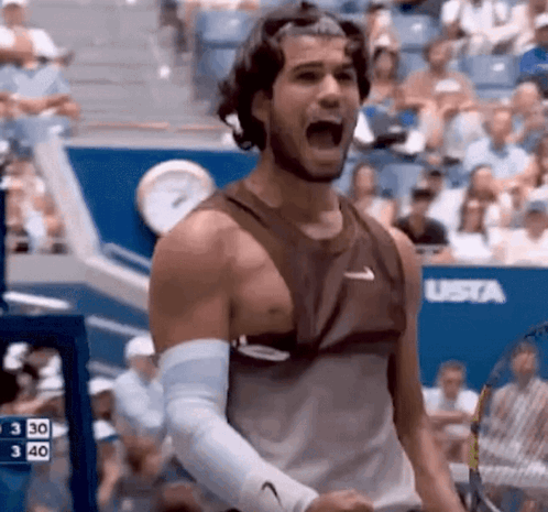 a man in a tank top is holding a tennis racquet and shouting .