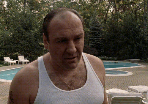 A Man In A Tank Top Stands In Front Of A Swimming Pool GIF