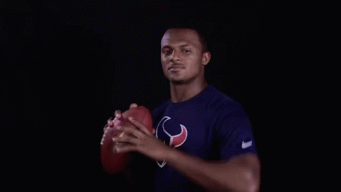 A Man In A Texans Shirt Is Holding A Football In His Hand . GIF