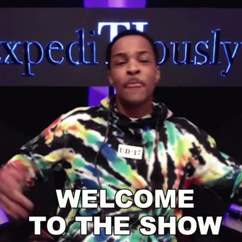 A Man In A Tie Dye Shirt Says Welcome To The Show In Front Of A Sign That Says Expeditously GIF