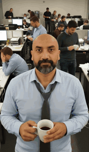 A Man In A Tie Holds A Cup Of Coffee In An Office GIF