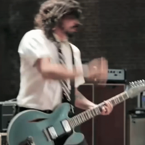 A Man In A Tie Is Playing A Guitar GIF