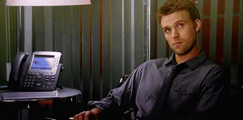 A Man In A Tie Is Sitting In Front Of A Desk With A Telephone . GIF