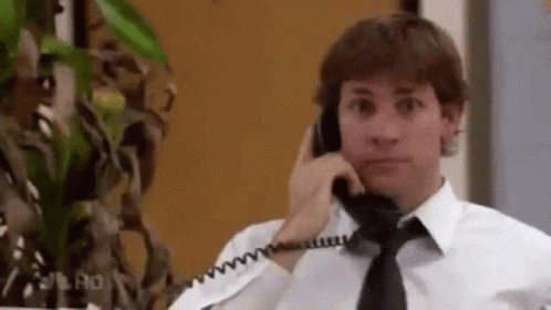 A Man In A Tie Is Talking On A Phone . GIF