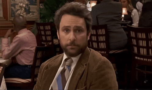 A Man In A Tie Sits At A Table With A Bottle Of Beer On It GIF