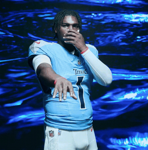 a man in a titans jersey covering his mouth