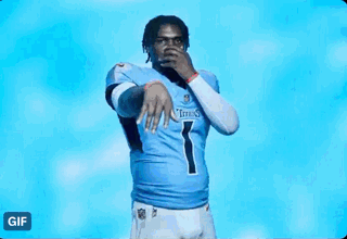 a man in a titans jersey is standing in front of a blue light .