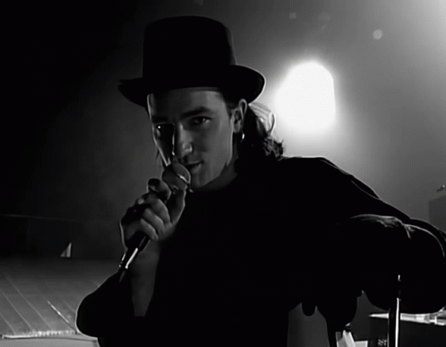 a man in a top hat is singing into a microphone in a black and white photo