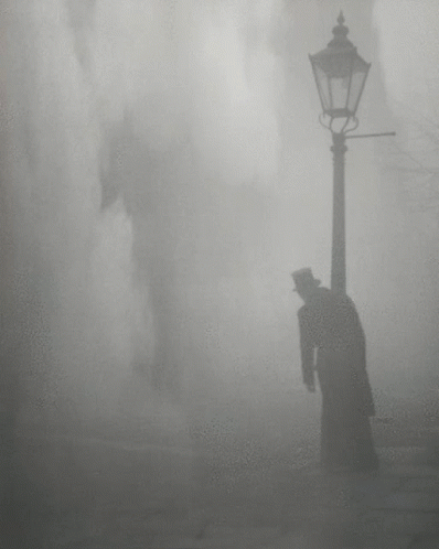 A Man In A Top Hat Is Standing Next To A Street Light GIF