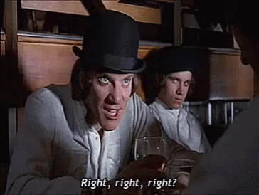 A Man In A Top Hat Is Talking To Another Man While Holding A Glass Of Wine . GIF