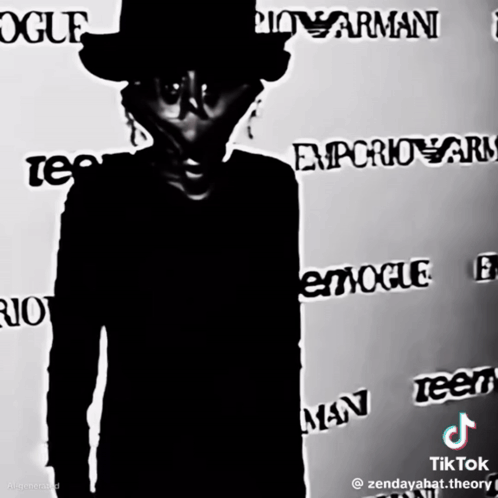 A Man In A Top Hat Stands In Front Of A Wall That Says Vogue GIF