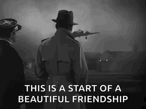 a man in a trench coat and hat is standing next to a man in a hat looking at a plane taking off .