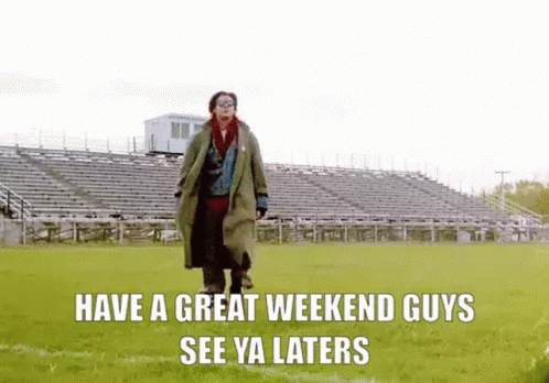 A Man In A Trench Coat Is Walking On A Field With A Stadium In The Background . GIF