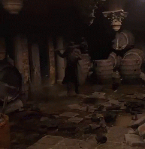 A Man In A Trench Coat Is Walking Through A Dark Room GIF