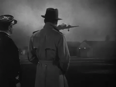 a man in a trench coat stands in front of a plane that says jet