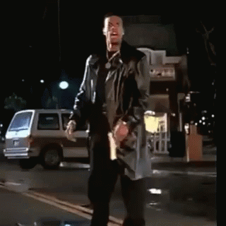 A Man In A Trench Coat Stands On A Street At Night GIF