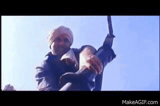 A Man In A Turban Is Holding A Large Sword In His Hand . GIF