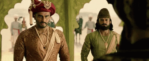 A Man In A Turban Is Standing Next To Another Man In A Costume . GIF