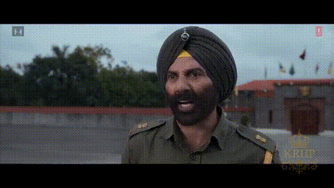 A Man In A Turban With A Beard Is Standing In Front Of A Building GIF