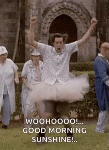 A Man In A Tutu Is Jumping In The Air With His Arms In The Air And A Group Of People Standing Behind Him . GIF