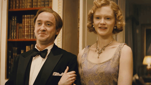 A Man In A Tuxedo And A Woman In A Purple Dress Pose For A Picture GIF