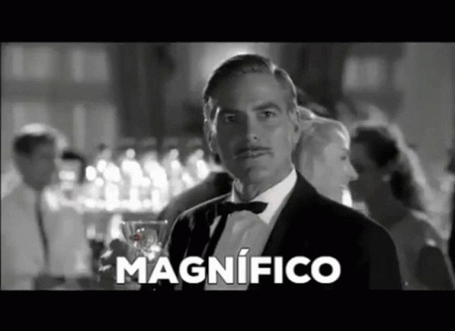 A Man In A Tuxedo And Bow Tie Is Holding A Glass Of Wine And Says Magnifico In Spanish . GIF