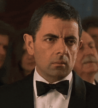 A Man In A Tuxedo And Bow Tie Is Looking At Something GIF