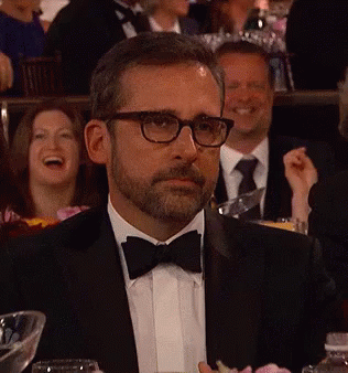 A Man In A Tuxedo And Bow Tie Is Sitting At A Table With Other People GIF