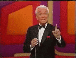 A Man In A Tuxedo And Bow Tie Is Speaking Into A Microphone GIF