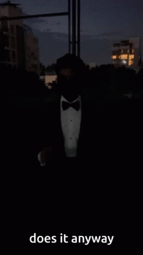 A Man In A Tuxedo And Bow Tie Is Standing In The Dark And Says Does It Anyway GIF