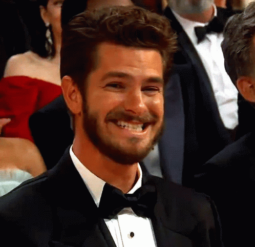 a man in a tuxedo and bow tie smiles in a crowd
