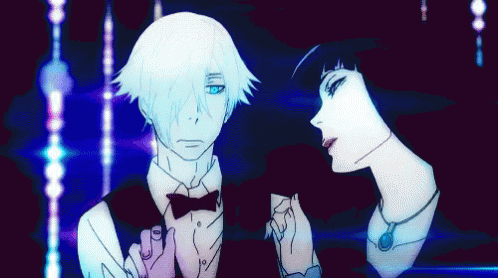 A Man In A Tuxedo And Bow Tie Stands Next To A Woman In A Black Dress GIF