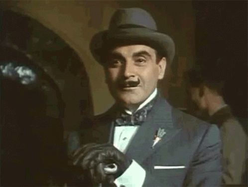 A Man In A Tuxedo And Hat Is Holding His Gloves GIF