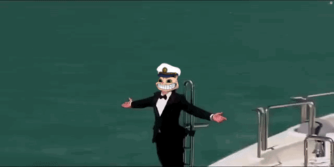 A Man In A Tuxedo And Hat Is Standing On The Side Of A Yacht . GIF