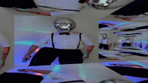 A Man In A Tuxedo And Suspenders Is Standing In A Room With A Disco Ball On His Head GIF