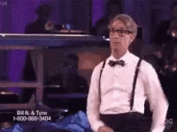 A Man In A Tuxedo And Suspenders Is Standing In Front Of A Phone Number GIF