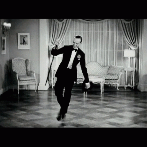 A Man In A Tuxedo Dancing In A Living Room GIF