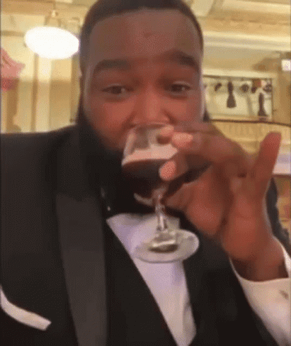 A Man In A Tuxedo Drinking From A Glass GIF