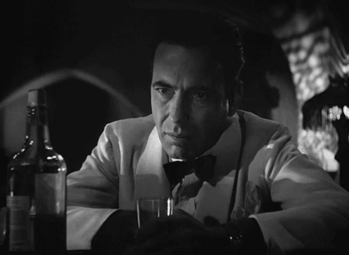 a man in a tuxedo holds a glass and a bottle