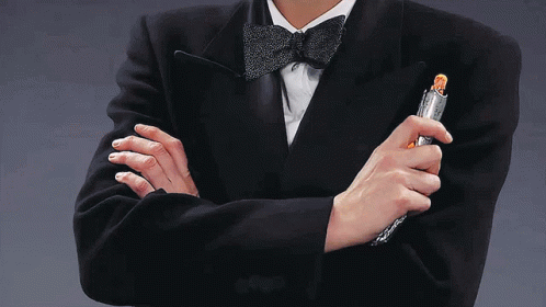 A Man In A Tuxedo Holds A Lighter In His Hand GIF