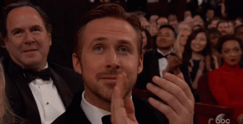 A Man In A Tuxedo Is Applauding While Sitting In A Crowd Of People . GIF