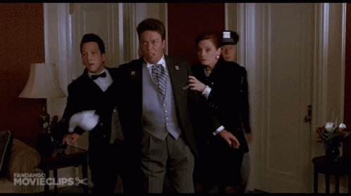 A Man In A Tuxedo Is Being Escorted By A Woman And A Man In A Police Uniform GIF